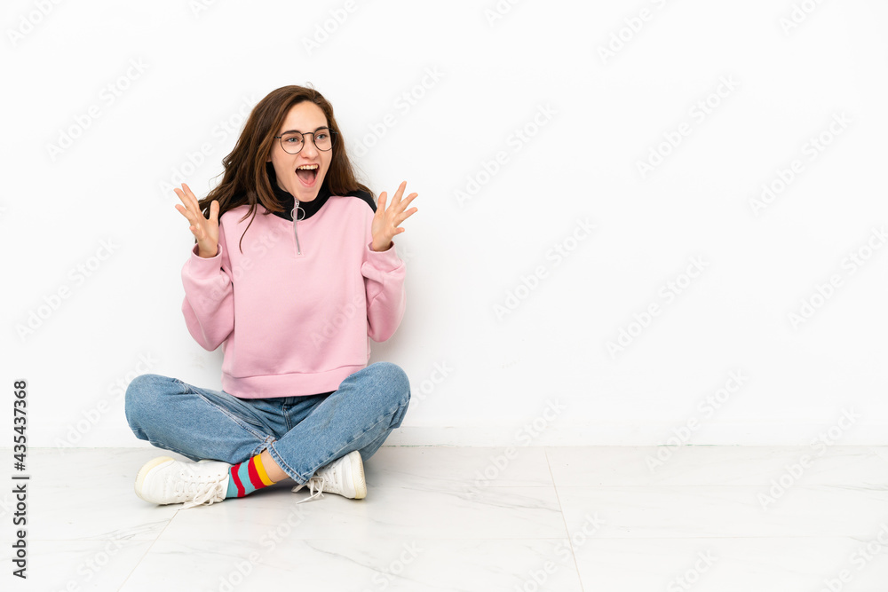 Young caucasian woman sitting on the floor isolated on white background with surprise facial expression Young caucasian woman sitting on the floor isolated on white background with surprise facial expression