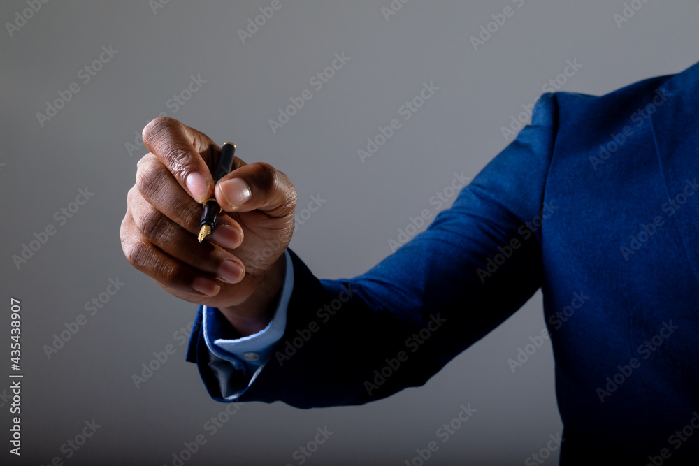 Fototapeta premium Mid section of businessman writing on invisible screen against grey background