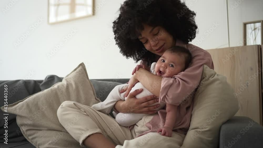 Woman babysitting her child on comfortable sofa at home, hold infant in arms and rock lull. Spbd Woman babysitting her child on comfortable sofa at home, hold infant in arms and rock lull. Spbd