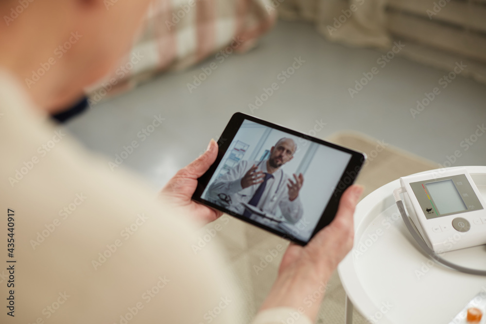 Telemedicine concept. Old woman with tablet during an online consultation with her doctor in her living room