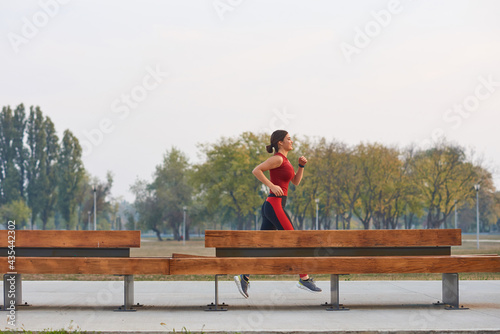 Young sporty woman jogging in urban park.