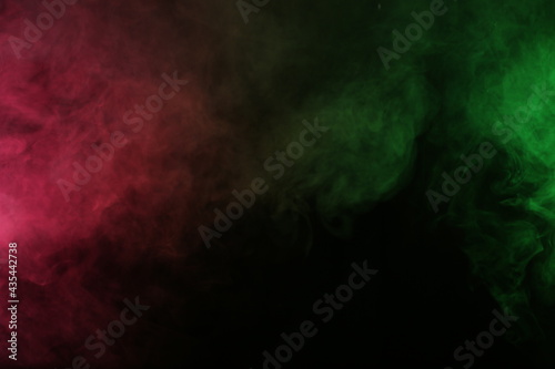 Artificial magic smoke in red-green light on black background