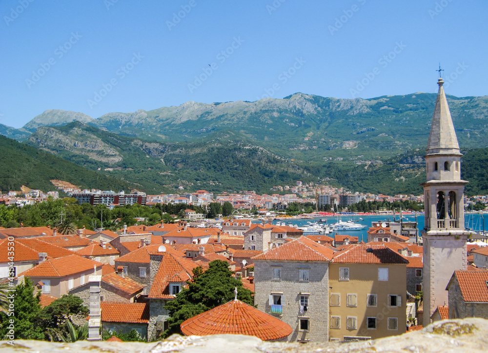 View from the top of fortress on the Budva Riviera-the old town, houses with tiled roofs, the sea bay with white yachts. And a city on the background of green mountains