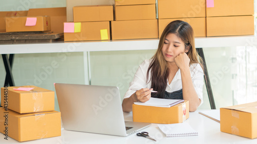 Small business owners working with laptops and cardboard boxes at work Small business entrepreneurs SME working with boxes at home selling online e-commerce