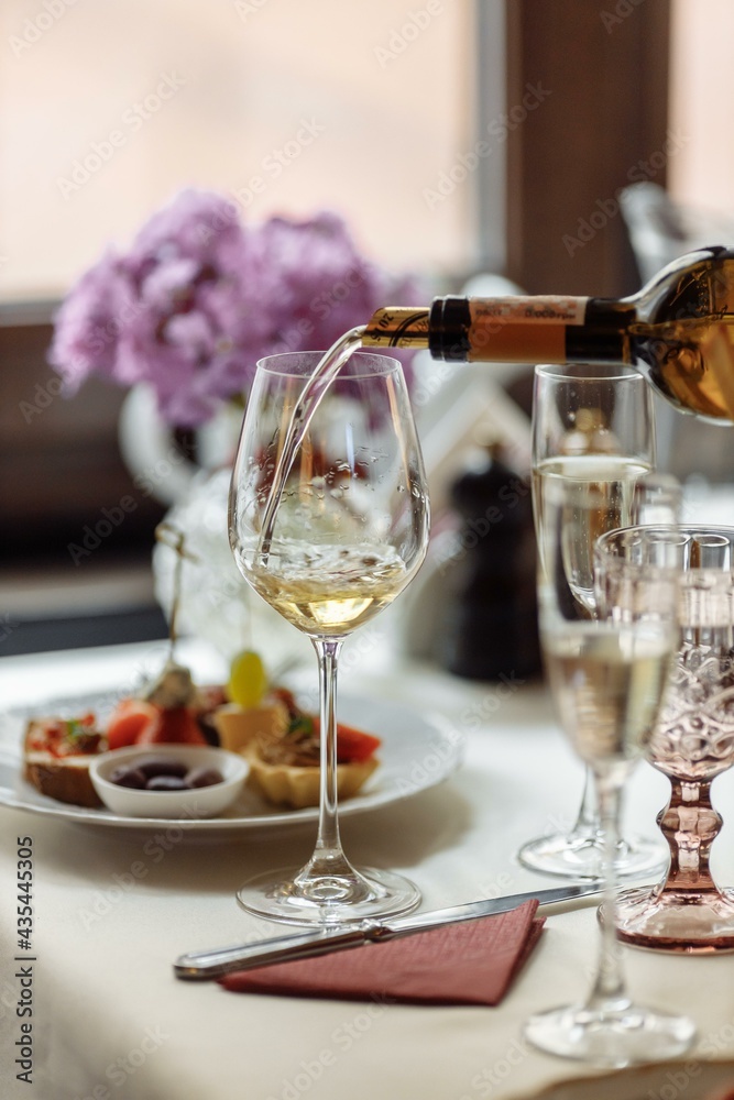 Waiter serving red wine in a fine dinning restaurant with happy female customer sitting at table Waiter serving red wine in a fine dinning restaurant with happy female customer sitting at table
