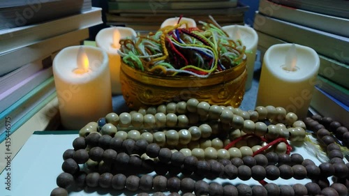 Yellow candlelight was swaying amid the surrounding prayer books. There is a necklace of yellow rosary and black sheath giving the idea of ​​the occult prayer.