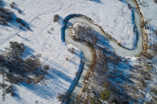 Beautiful Sunny landscape with forest, snow and frozen river. Aerial photography from a drone