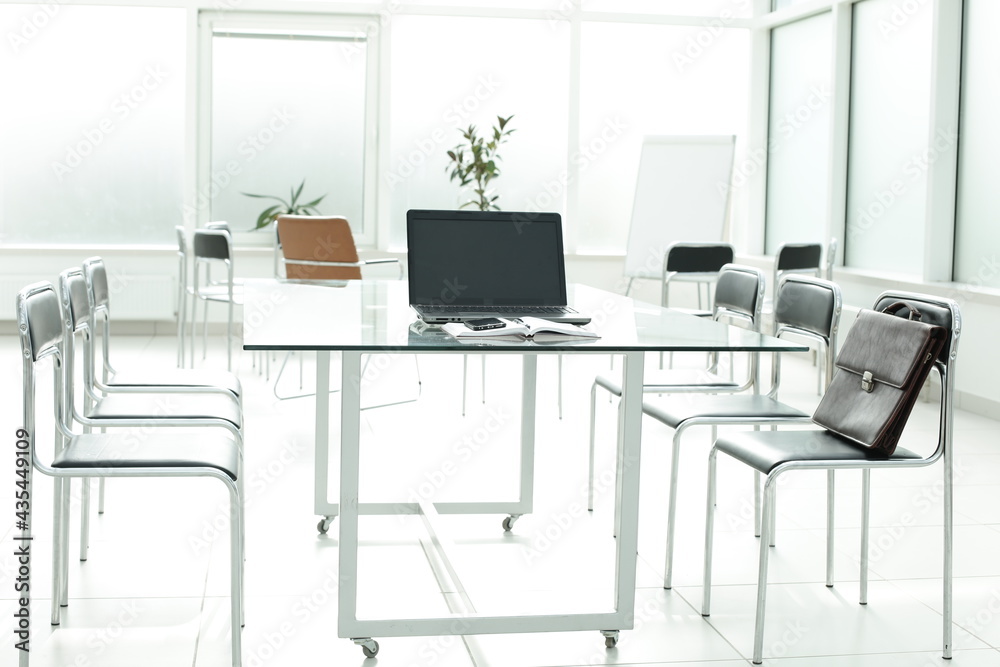 Flipchart laptop chairs and glass table in a bright office space Flipchart laptop chairs and glass table in a bright office space