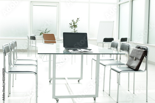 Flipchart laptop chairs and glass table in a bright office space