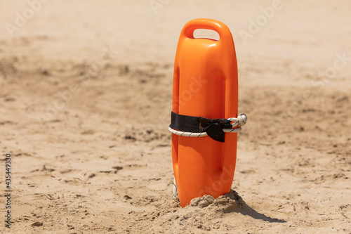 An orange rescue buoy, tipped into the sand, ready to be used in any relief and rescue action, on the beach of Torrenostra, Castellon province, Valencian Community.