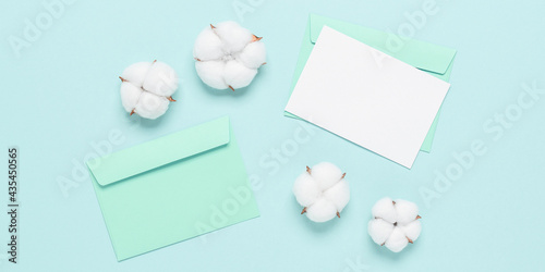 Blank white card mockup and cotton flowers on a mint blue pastel paper background. Delicate wedding template. Top view, flat lay, copy space. Banner
