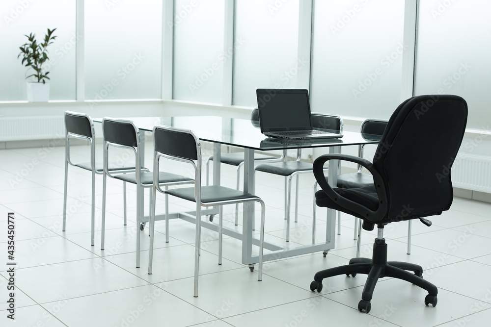 Grey laptop on glass table in office space