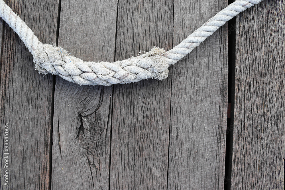 Ship ropes tied to knot isolated on wooden background closeup.
