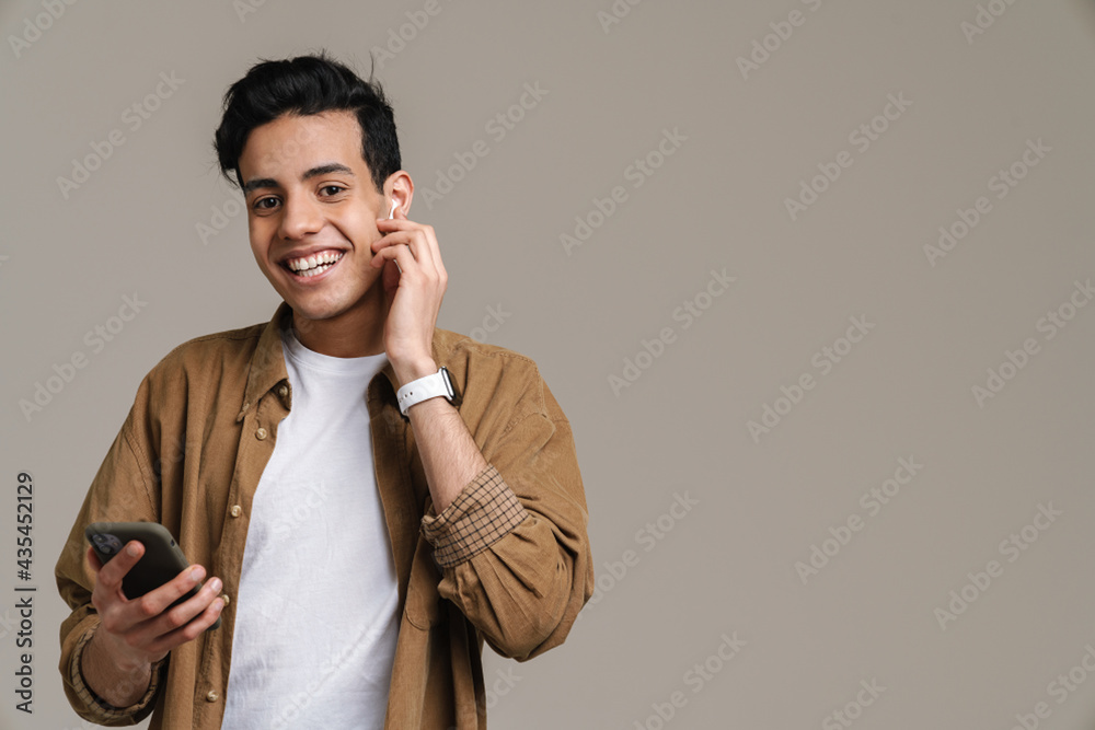 Brunette hispanic man smiling while using cellphone and earphones Brunette hispanic man smiling while using cellphone and earphones