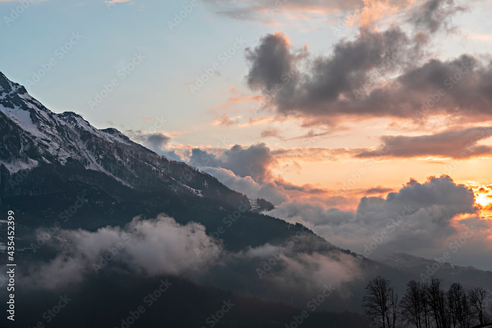 mountain view of the snow capped peaks of Caucasus Mountains in clouds at sunset, landscape, beauty in nature, copy space, cloudscape, natural background
