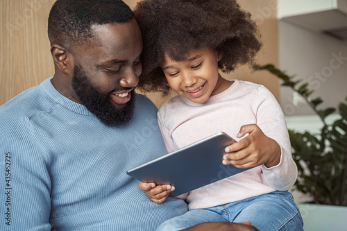 Closeup portrait of happy smiling dad and daughter watching video on tablet