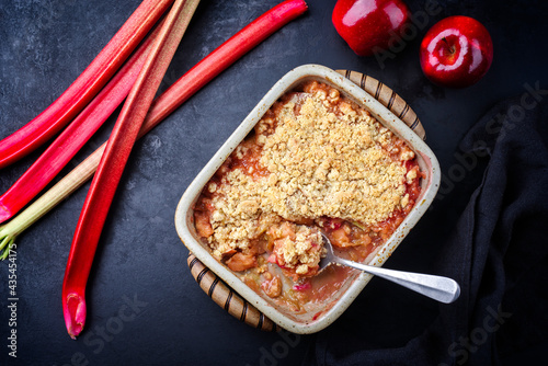 Traditional English crumble cake with rhubarb and apple with backed topping served as top view in backing form