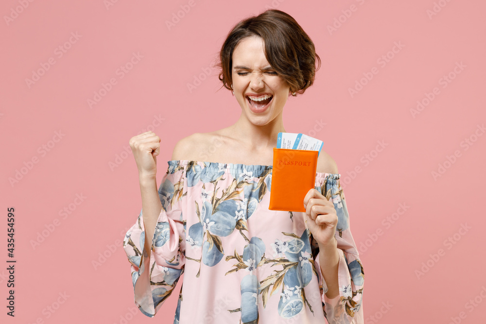 Traveler tourist happy woman wear blouse hold passport tickets do winner gesture clench fist isolated on pastel pink background. Passenger travel abroad on weekends getaway Air flight journey concept Traveler tourist happy woman wear blouse hold passport tickets do winner gesture clench fist isolated on pastel pink background. Passenger travel abroad on weekends getaway Air flight journey concept