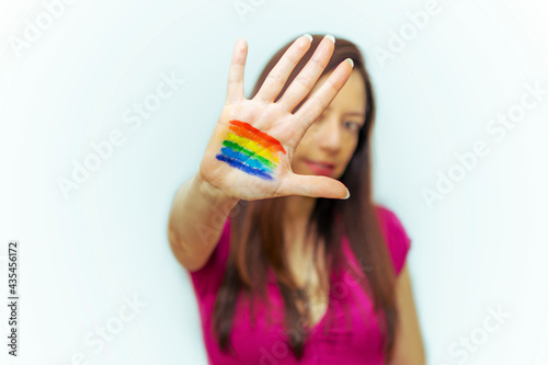 Young woman with the LGTBIQ+ flag painted on her hand.selective focus on hand and white background.