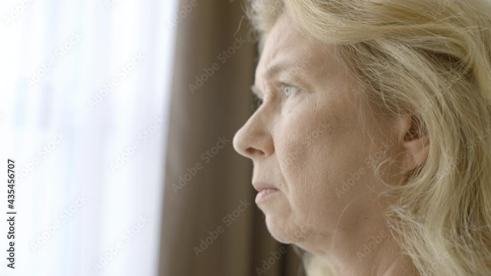 Melancholic mature woman looking out of window, feeling stress and depression Melancholic mature woman looking out of window, feeling stress and depression