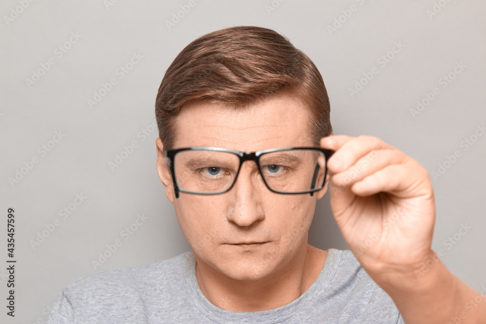 Portrait of serious man peering through glasses at something Portrait of serious man peering through glasses at something