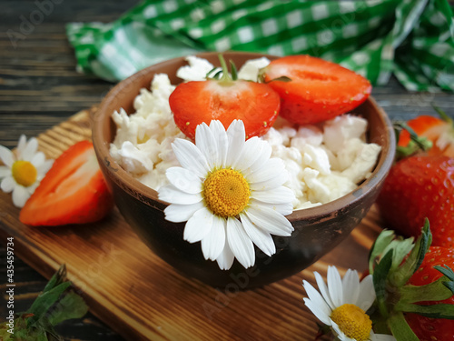cottage cheese, strawberry, chamomile flower on a wooden background