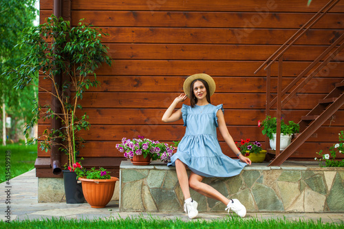 Brunette woman in a turquoise summer dress sits on the porch