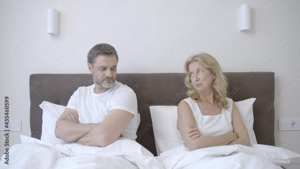 Middle-aged couple hugging in bed after quarrel, relationship, family life Middle-aged couple hugging in bed after quarrel, relationship, family life