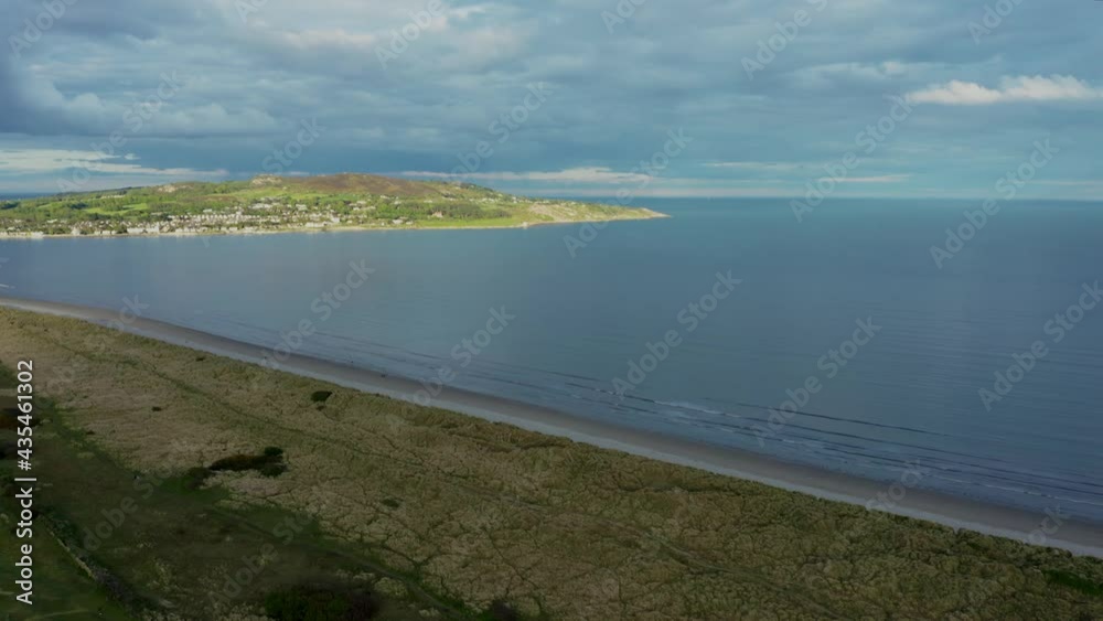 Drone aerial view moving forward over marram grass anchored dunes revealing Dollymount Strand beach and Howth peninsula. Drone aerial view moving forward over marram grass anchored dunes revealing Dollymount Strand beach and Howth peninsula.