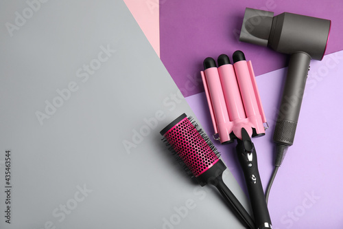 Fototapeta Naklejka Na Ścianę i Meble -  Hair dryer, brush and triple curling iron on color background, flat lay. Space for text