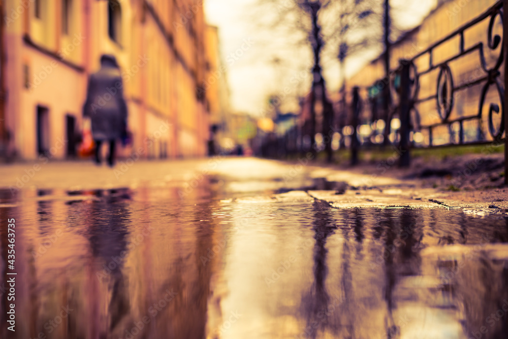 Streets in the late autumn, pedestrians walk on the sidewalk. The view from the sidewalk level