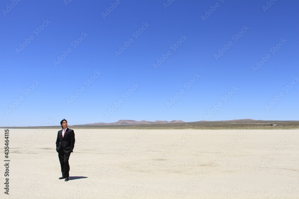 A young businessman standing in a vast desert A young businessman standing in a vast desert