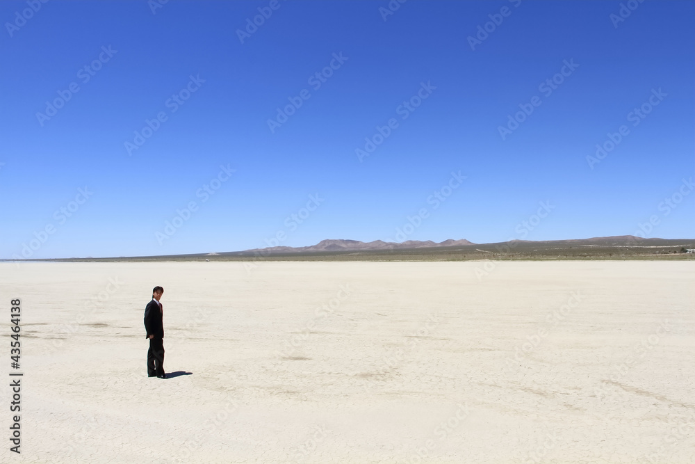 A young businessman standing in a vast desert 