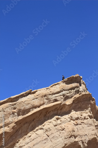 Young businessman standing on a huge rock 