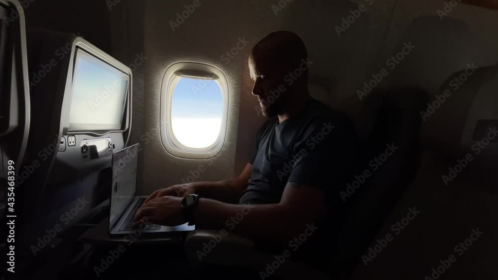 Man working on his laptop while flying in the airplane Man working on his laptop while flying in the airplane