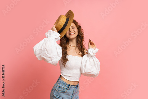 Summer studio portrait of cheerful red haired lady in fashionable outfit having fun on pink background. Perfect wavy hairs.