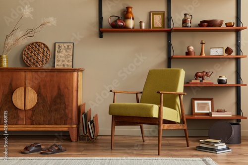 Modern retro concept of living room interior with stylish armchair, wooden shelf, book, picture frame, decoration and elegant personal accessoreis in home decor. Template. Neutral background wall. © FollowTheFlow
