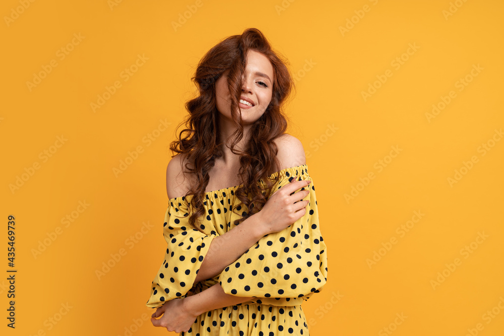 Stylish red-haired woman posing in yellow dress with sleeves over yellow background. Summer mood. Stylish red-haired woman posing in yellow dress with sleeves over yellow background. Summer mood.