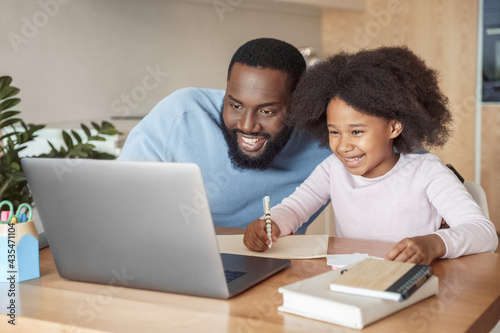 Head shot smiling father and daughter watching funny video studying at home