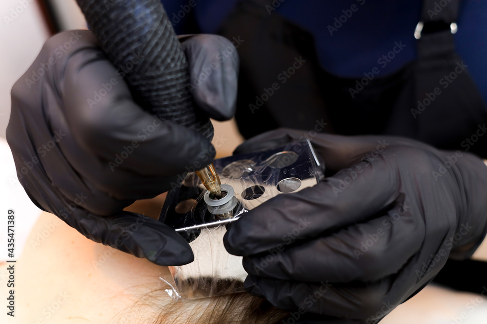 permanent makeup artist installs tattoo pigment in tattoo machine