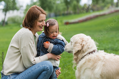 Obraz na plátne autistic child holding toy ball near mother and dog
