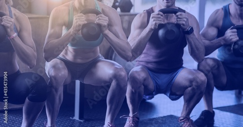 Composition of light blur over group of muscular men exercising with dumbbells
