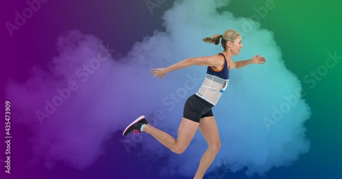 Composition of athletic woman running over smoke on colorful background © vectorfusionart