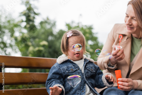 soap bubbles near autistic kid with mother on blurred bench © LIGHTFIELD STUDIOS