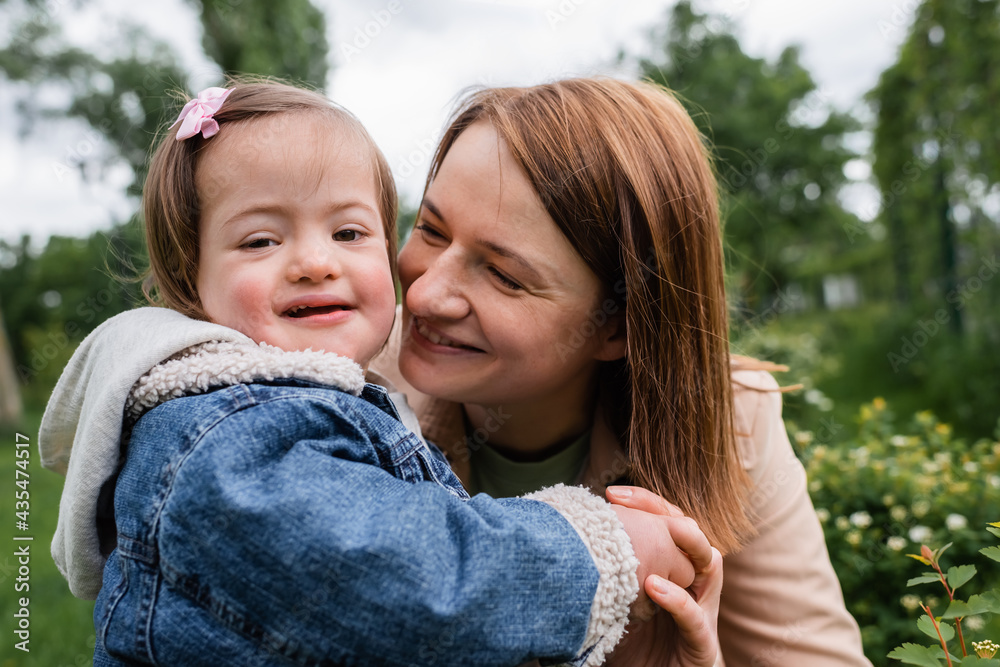 mother smiling and looking at child with disability in park mother smiling and looking at child with disability in park