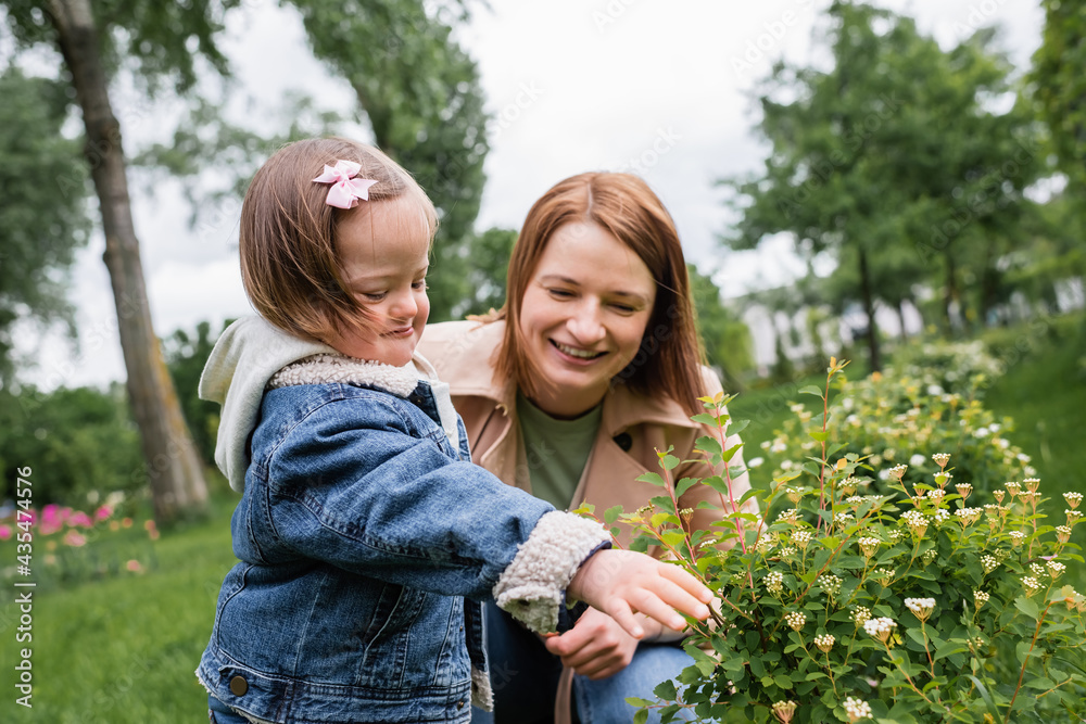 happy mother looking at bush near disabled daughter happy mother looking at bush near disabled daughter