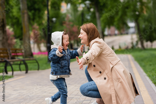 Fotografie excited autistic girl running to happy mother in park