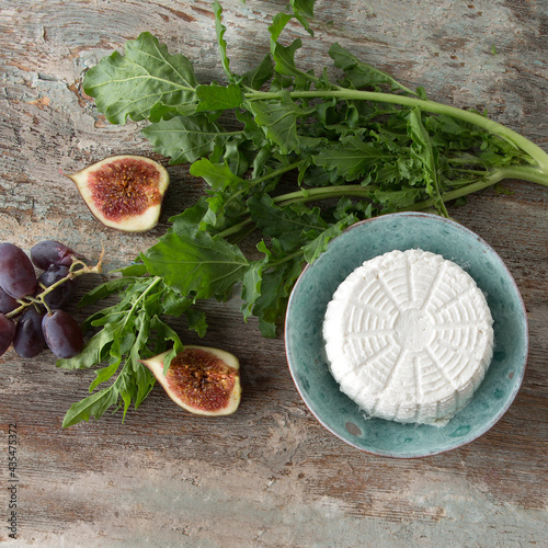 bowl with homemade ricotta cheese, figs and arugula on a wooden table