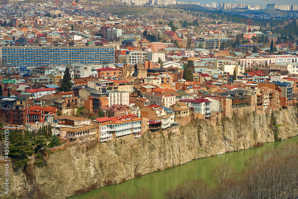 Old architecture of Tbilisi. Dense development of a residential building on a cliff by the river