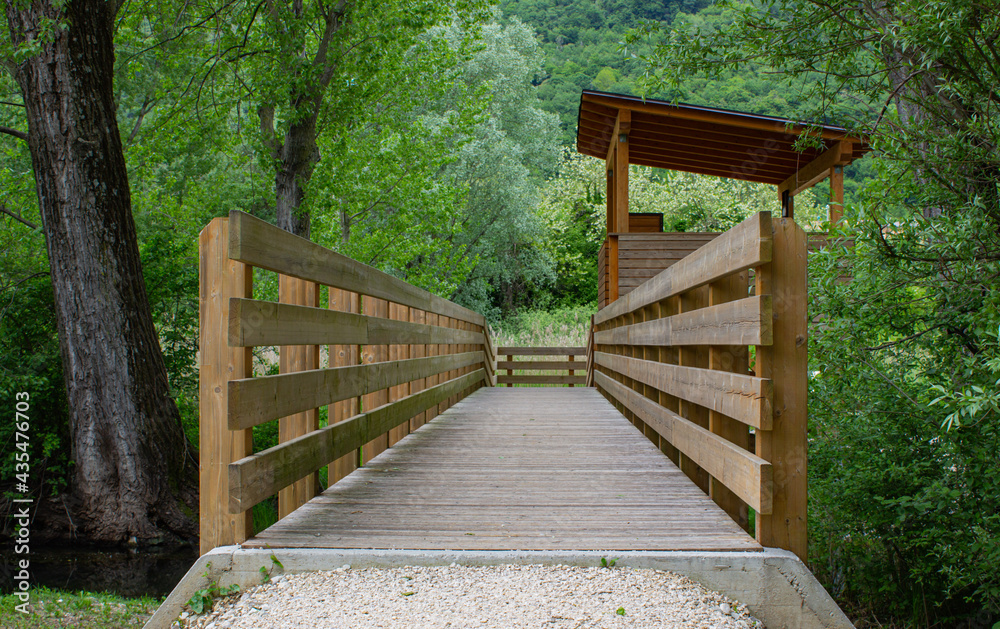 Wooden walkway over a canal in the middle of the park. Lakes of Revine Lago, Treviso, Italy Wooden walkway over a canal in the middle of the park. Lakes of Revine Lago, Treviso, Italy
